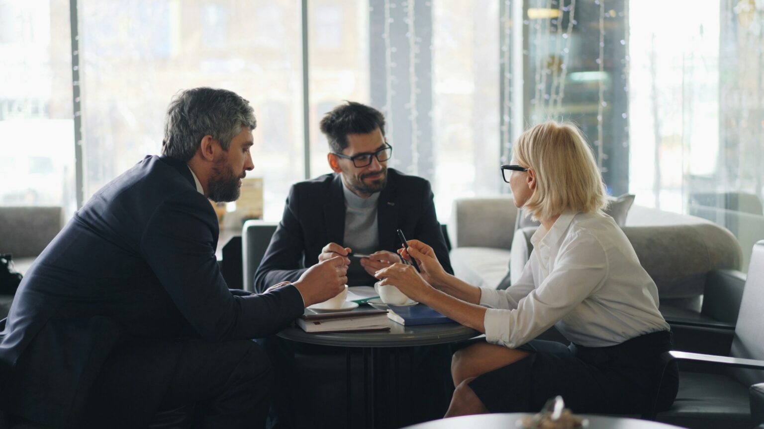 Three colleagues in business dress in discussion around a table